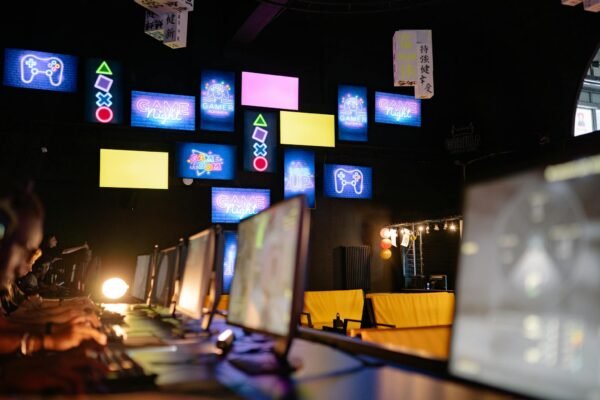 Illuminated gaming room with colorful screens and neon signs, creating an immersive gaming experience.