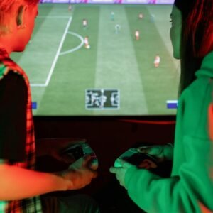 Two teenagers focused on playing a soccer video game at home.